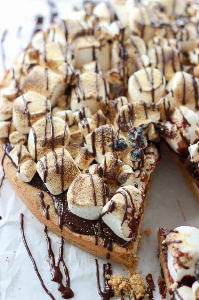 One giant graham cracker infused sugar cookie, topped with silky smooth chocolate ganache, and then loaded with marshmallows just waiting to be torched up. #smores #cookiecake #giantcookie Frostingandfettuccine.com