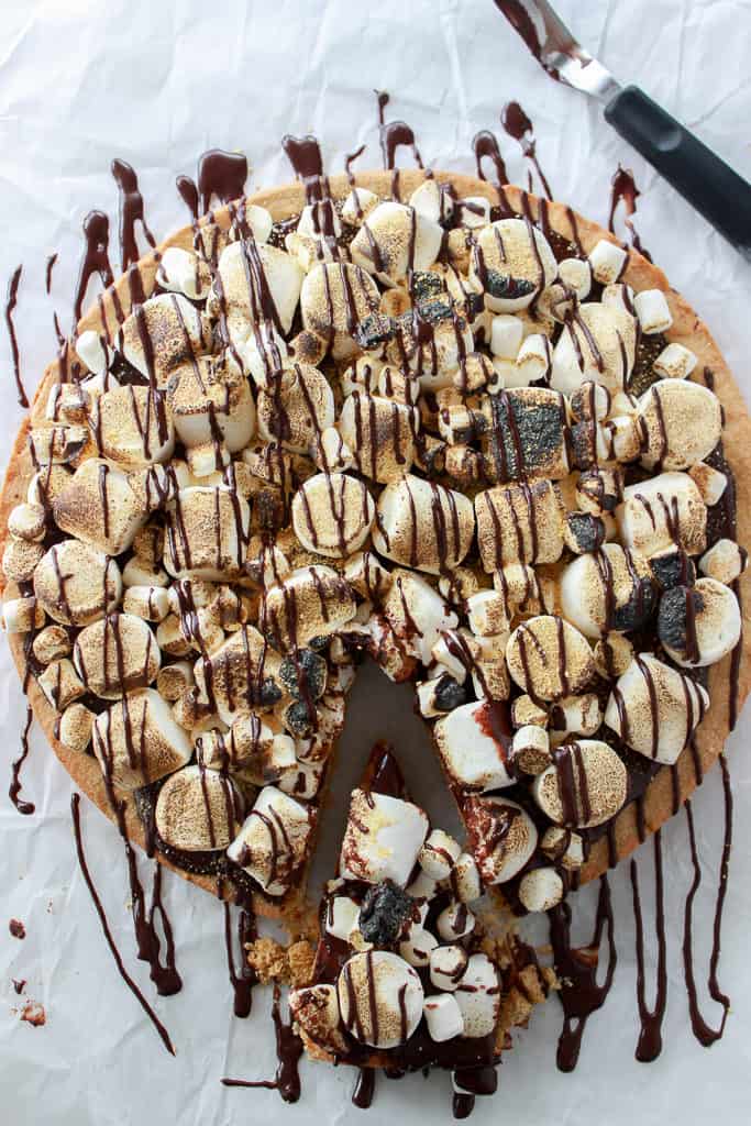 One giant graham cracker infused sugar cookie, topped with silky smooth chocolate ganache, and then loaded with marshmallows just waiting to be torched up. #smores #cookiecake #giantcookie Frostingandfettuccine.com