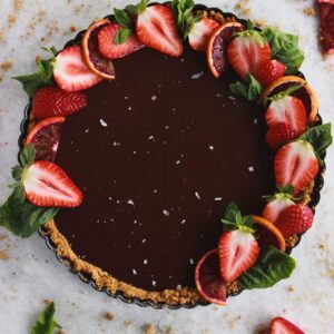 A chocolate tart topped with strawberries, sea salt, and sliced blood oranges