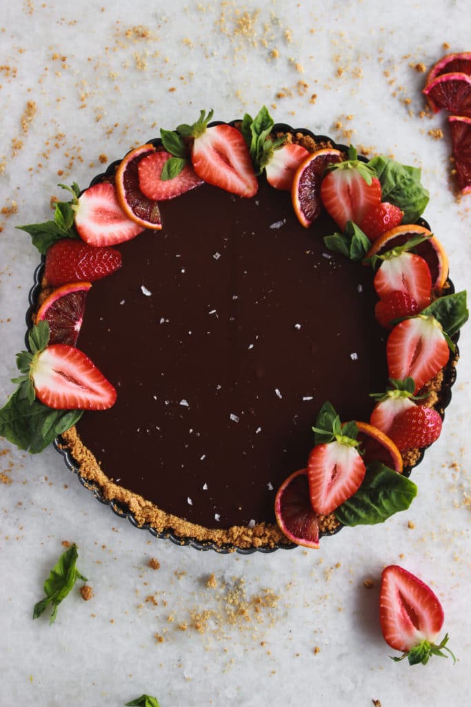 A chocolate tart topped with strawberries, sea salt, and sliced blood oranges