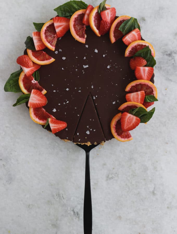 A chocolate tart topped with strawberries, sea salt, and sliced blood oranges