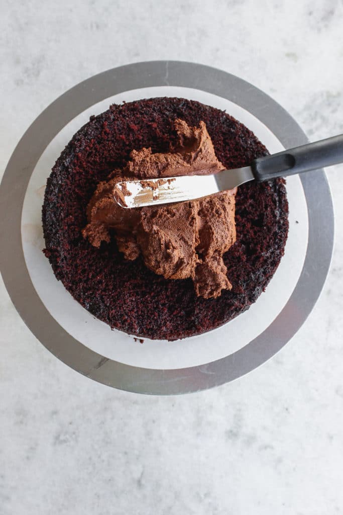 chocolate cake being frosted with chocolate buttercream