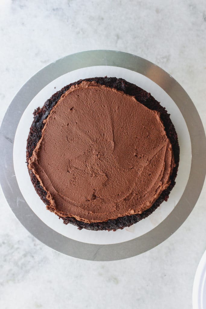 An overhead shot of chocolate frosting on top of a chocolate caking sitting on a cake stand