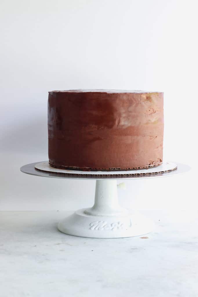 Chocolate frosted cake on a white cake stand