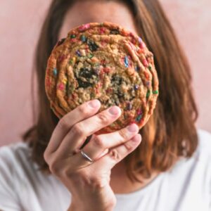 A girl holding a giant cookie up to her face