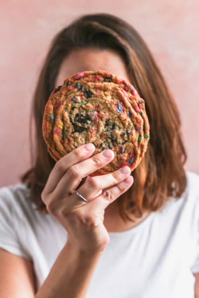 A girl holding a giant cookie up to her face