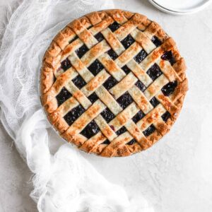 A beautiful picture of a semi homemade cherry pie with lattice crust fresh out of the oven.