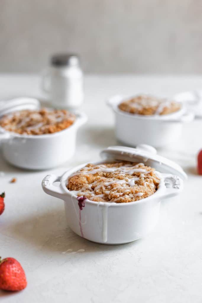 Triple berry coffee cakes baked inside mini staub cocottes on a white surface.