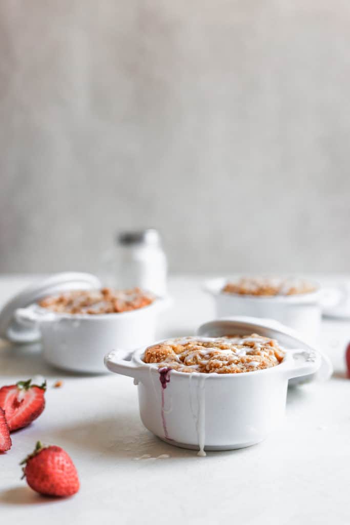 Triple berry coffee cakes baked inside mini staub cocottes on a white surface.