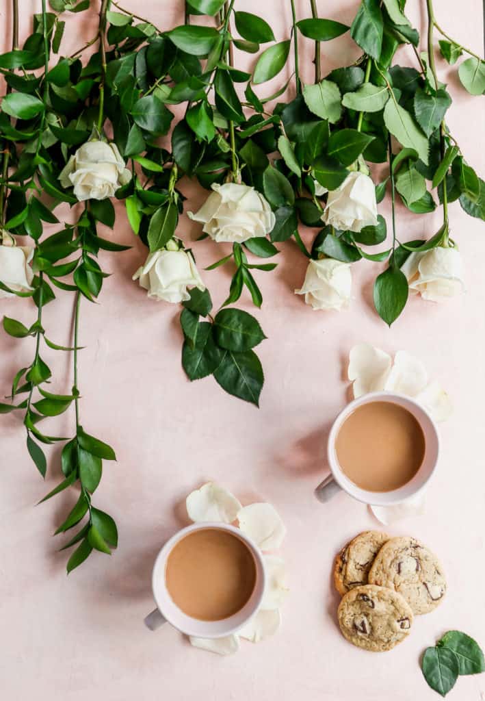 Coffe and cookies next to beautiful white rose and pink backdrop