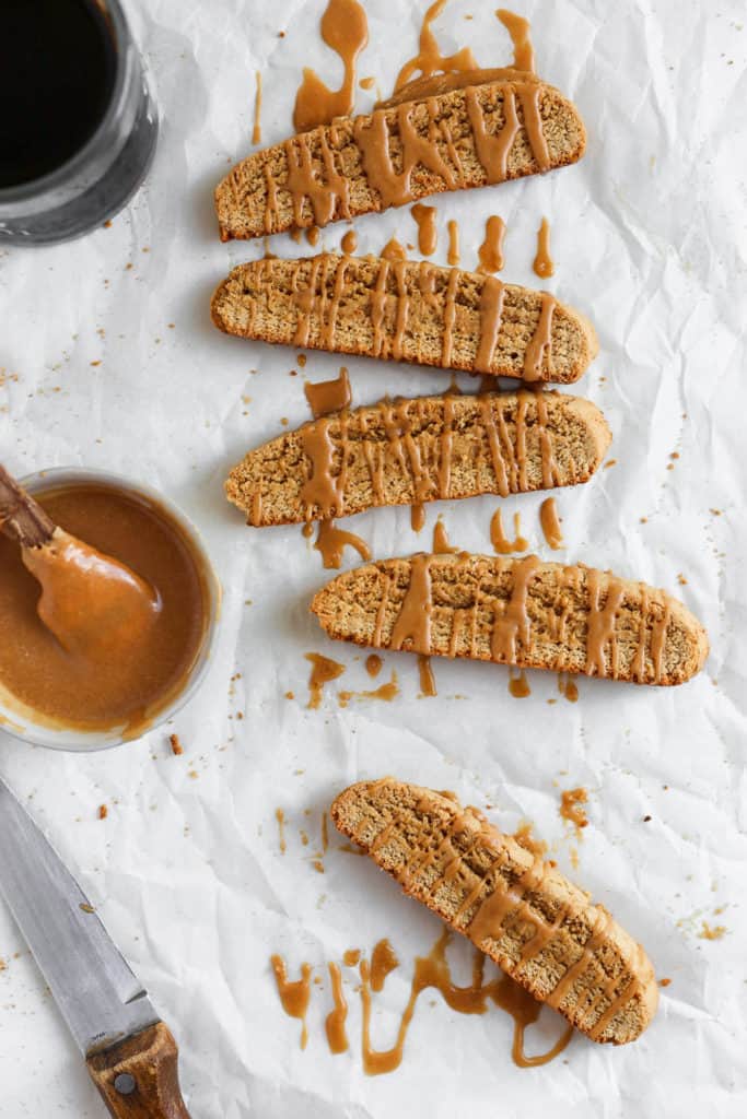 Fresh cookie butter biscotti cookies drizzled with a cookie butter glaze on a white background.