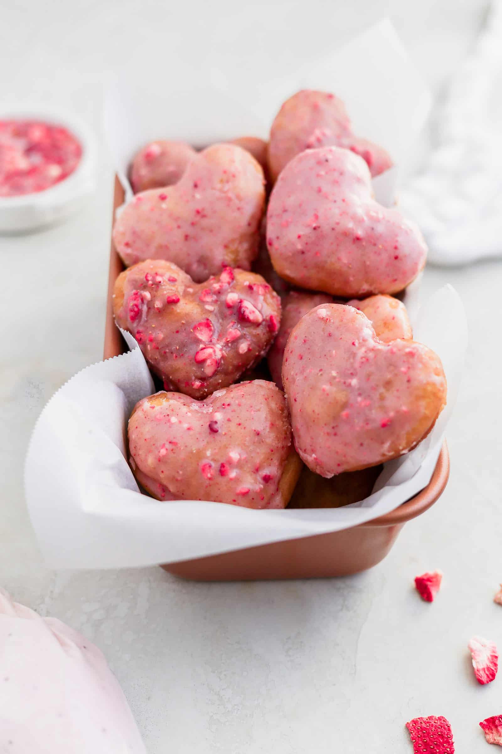 Pink strawberry heart shaped donuts arranged in a loaf pan.