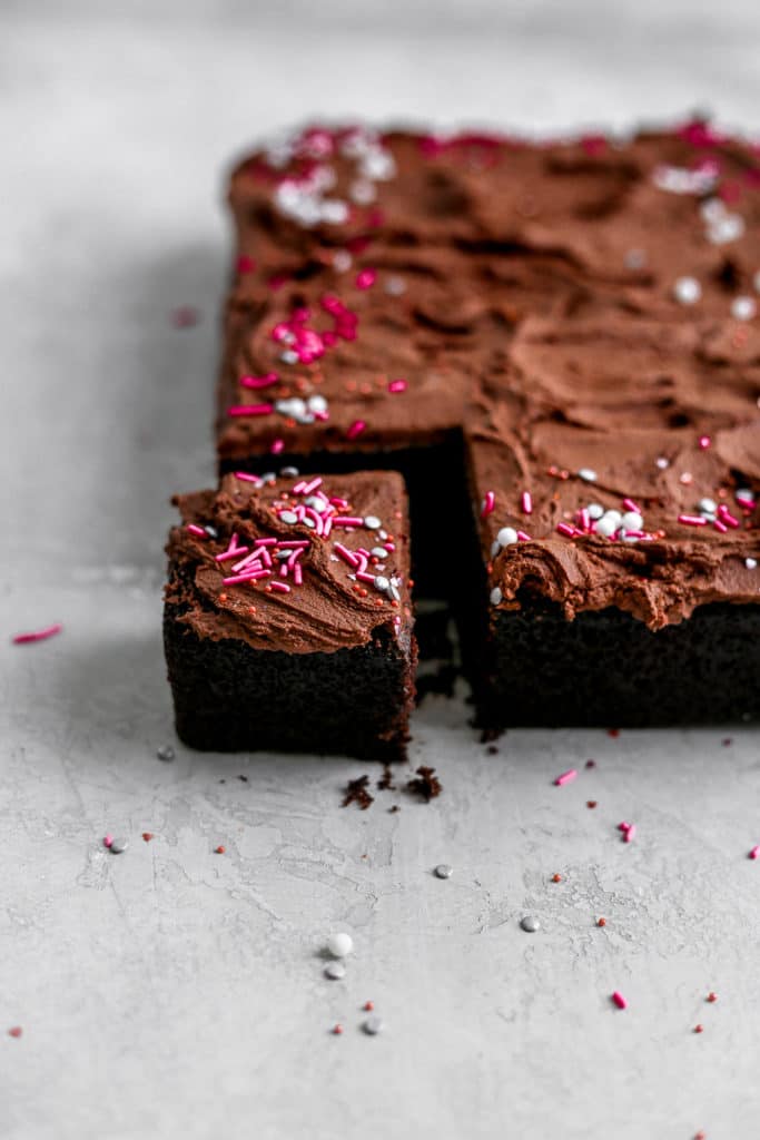 The corner piece of a one bowl chocolate cake cut off on a gray background.