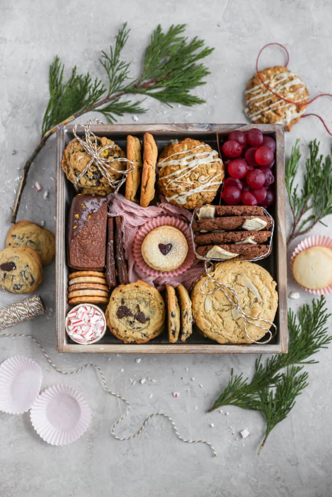 7 kinds of cookies arranged in a cookie gift box on a gray background decorated with leaves.