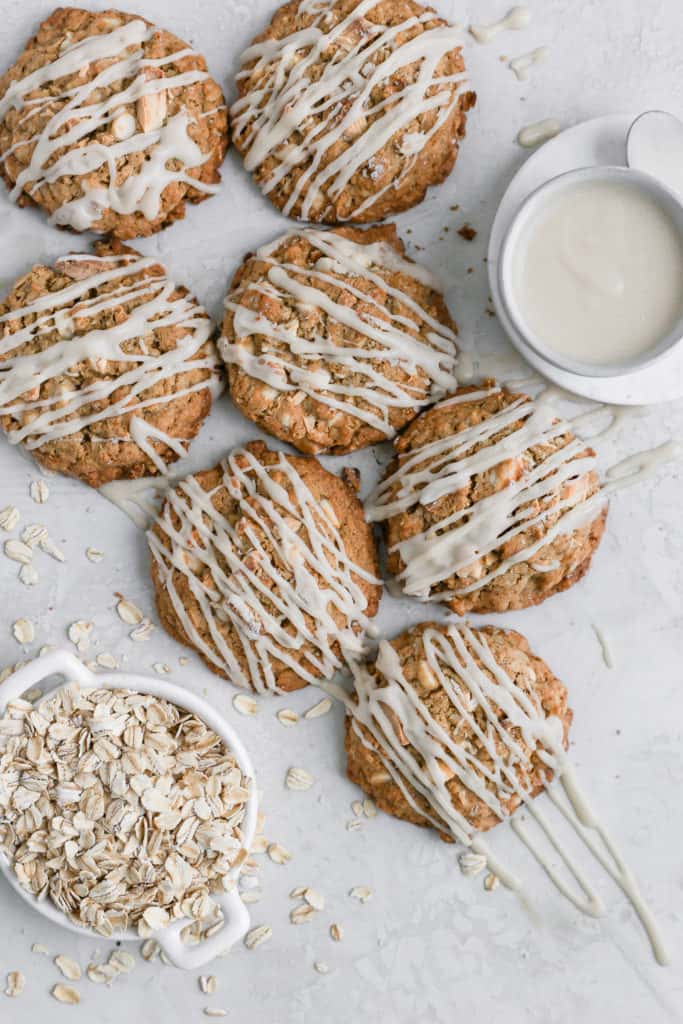 White chocolate oatmeal cookies topped with cream cheese glazes displayed on a gray background.