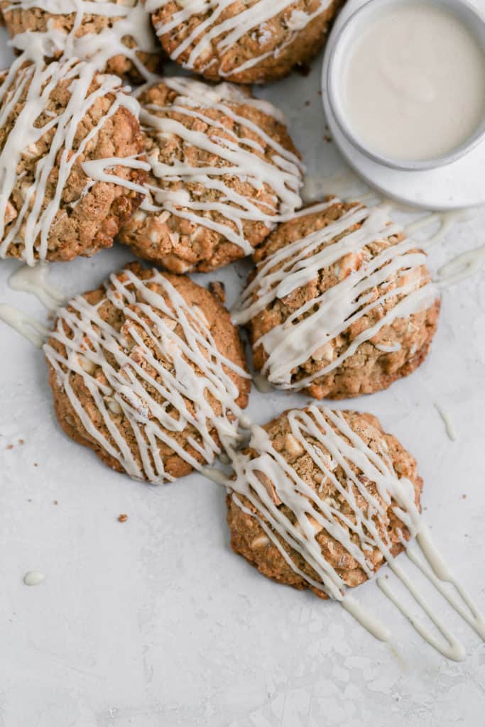 White chocolate oatmeal cookies topped with cream cheese glazes displayed on a gray background.