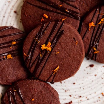 A closeup shot of a chocolate cookie on a white speckled plate.