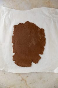 Chocolate cookie dough rolled out on a piece of parchment paper.