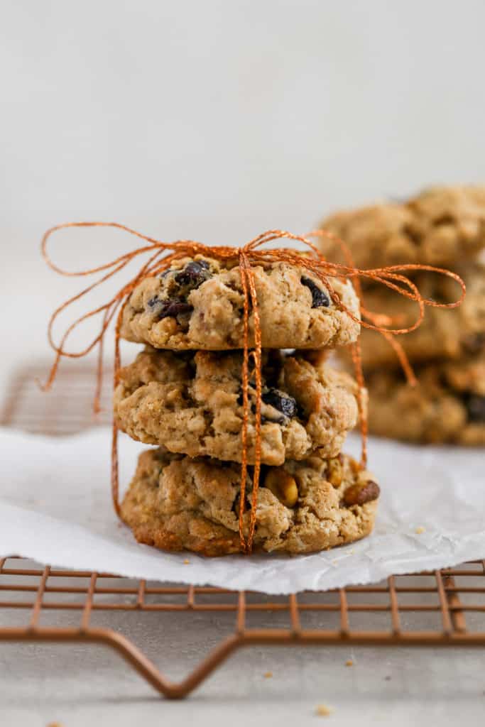 Cherry pistachio oatmeal cookies tied up with string displayed on a cookie rack.