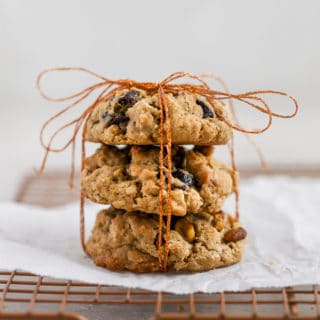 Cherry pistachio oatmeal cookies tied up with string displayed on a cookie rack.