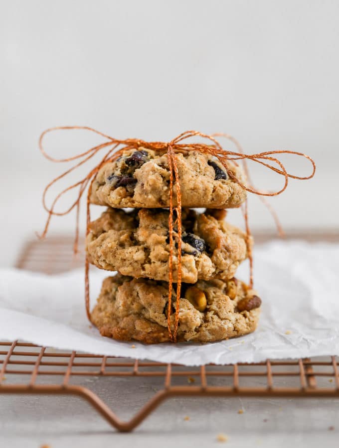 Cherry pistachio oatmeal cookies tied up with string displayed on a cookie rack.