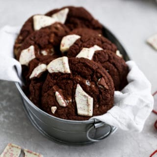 Double chocolate peppermint cookies sitting in a tin on a grey food photography background.