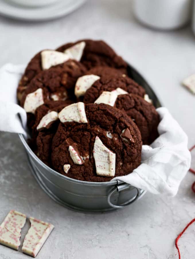 Chocolate cookies in linen lined tin on a gray surface
