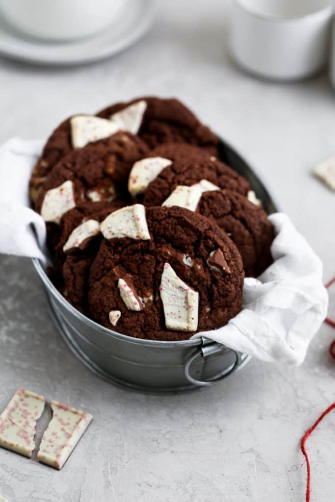 Chocolate cookies in linen lined tin on a gray surface