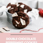Double chocolate peppermint cookies sitting in a tin on a grey food photography background.
