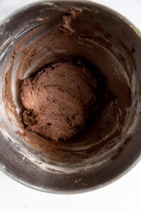 Chocolate cookie batter in a stainless steel bowl.