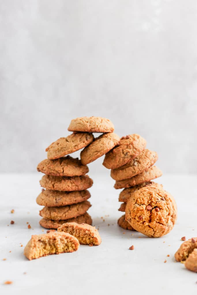 Chewy pumpkin maple cookies stacked on top of each other on a grey background.