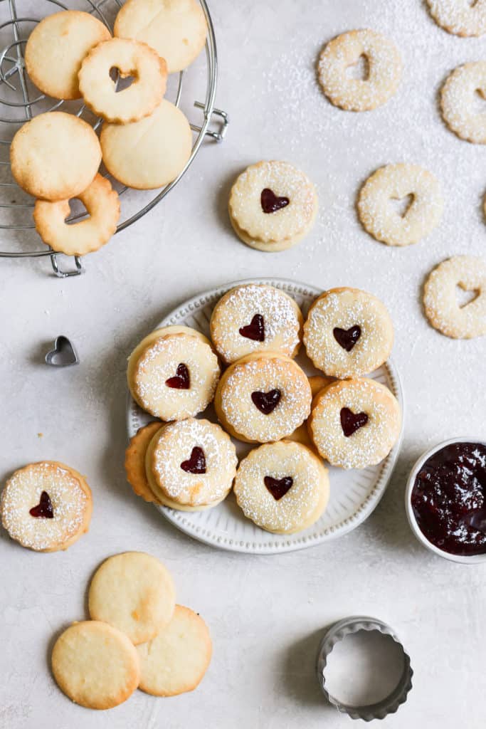 Raspberry lemon linzer cookie recipe displayed on a small plate on a grey background. 