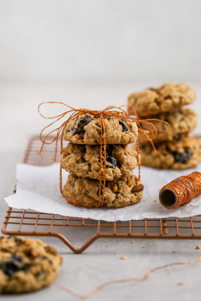 Cherry pistachio oatmeal cookies tied up with string displayed on a cookie rack.