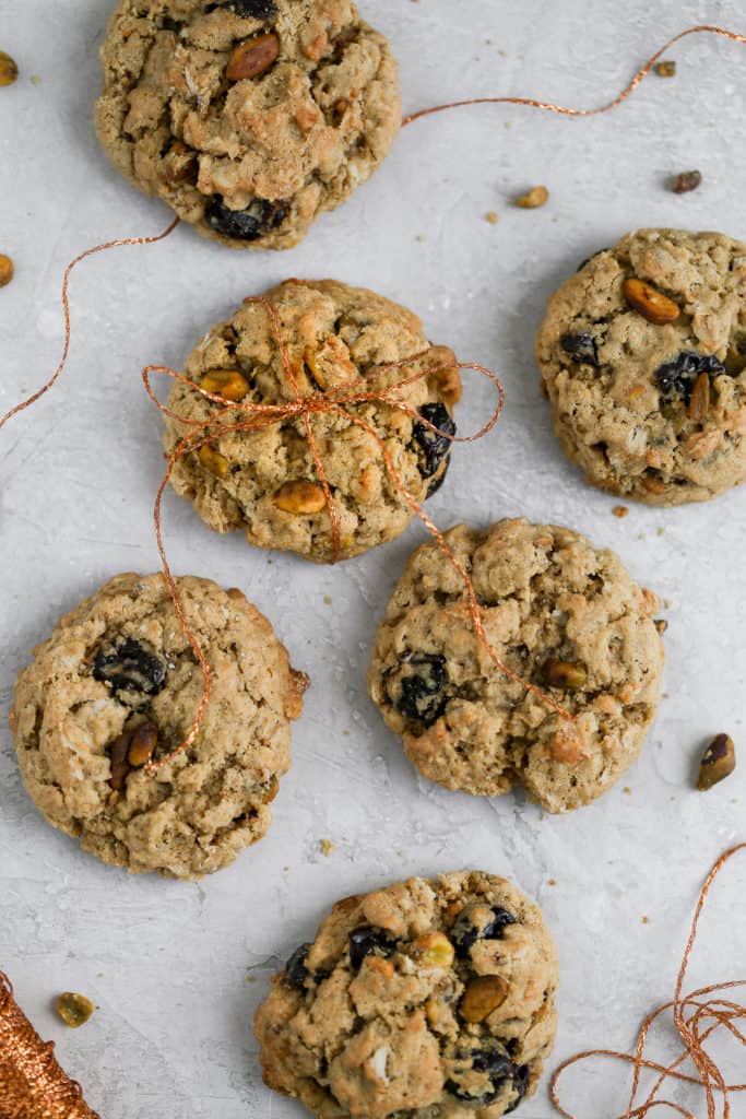 Cherry pistachio oatmeal cookies tied up with string displayed on a gray background