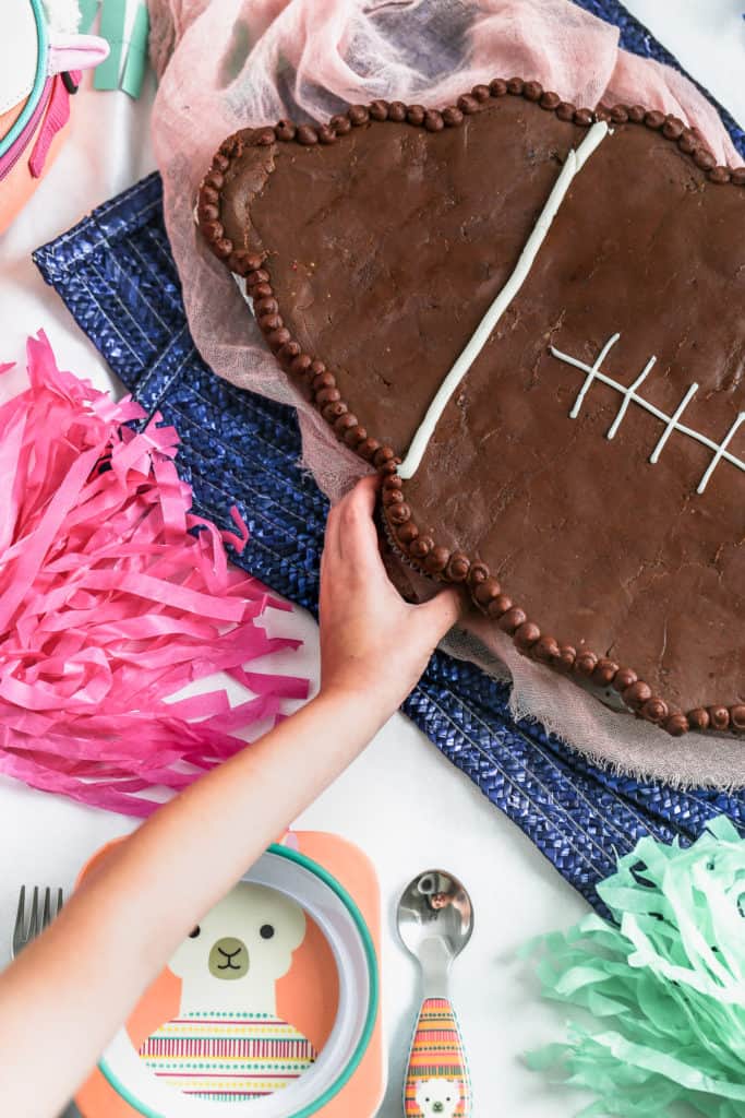 child reaching to pull a cupcake from a football cupcake cake