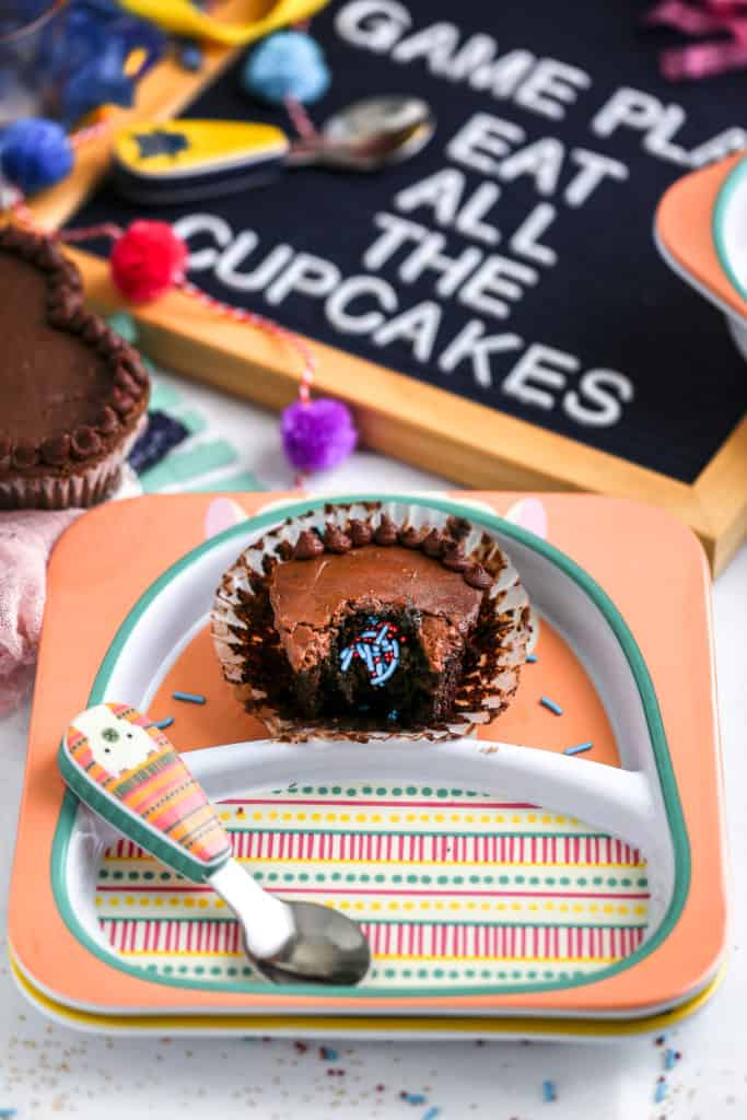 A chocolate cupcake with a sprinkle surprise inside styled on plates from Skip Hop for a football party.