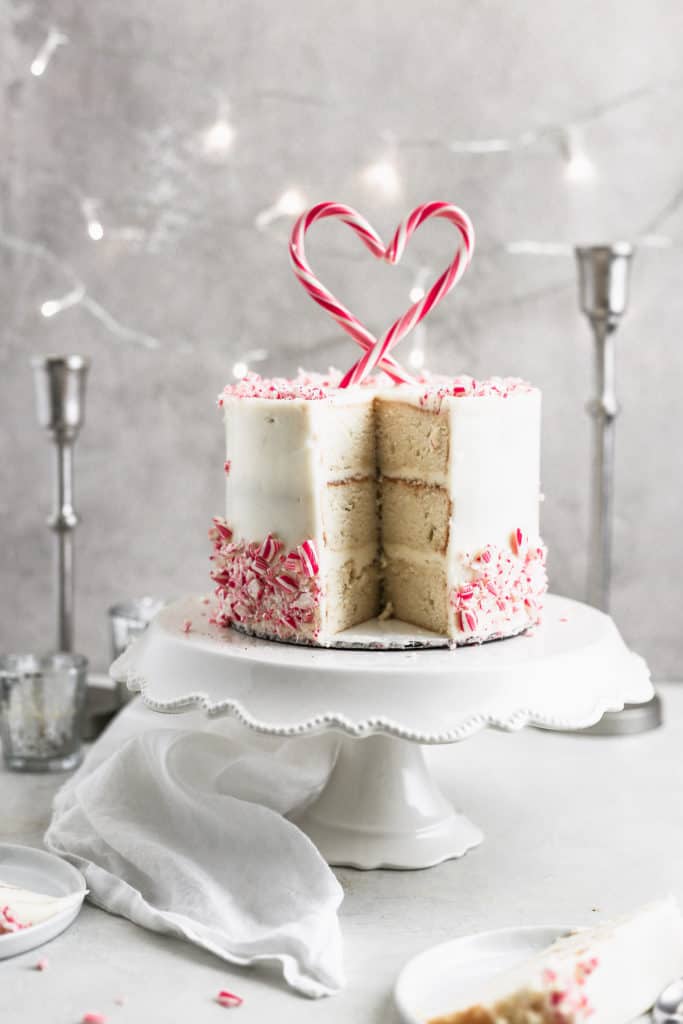 A peppermint cake with a slice taken out on a white cake stand.