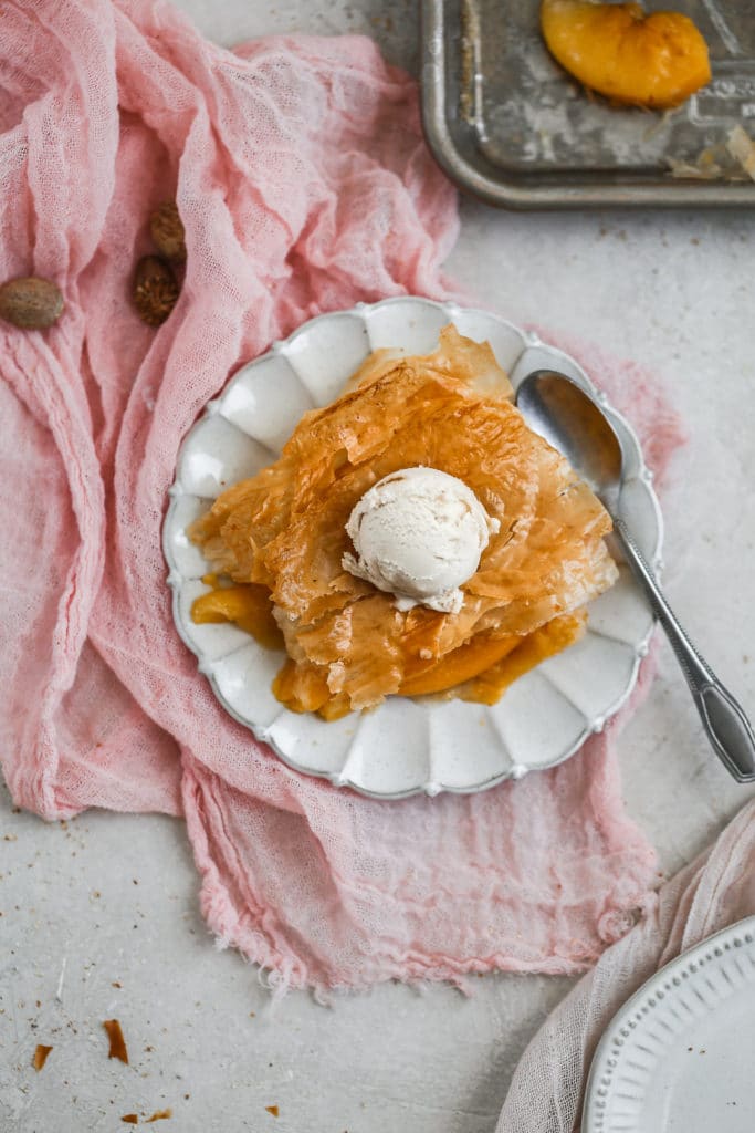 A flakey peach slab pie topped with ice cream.