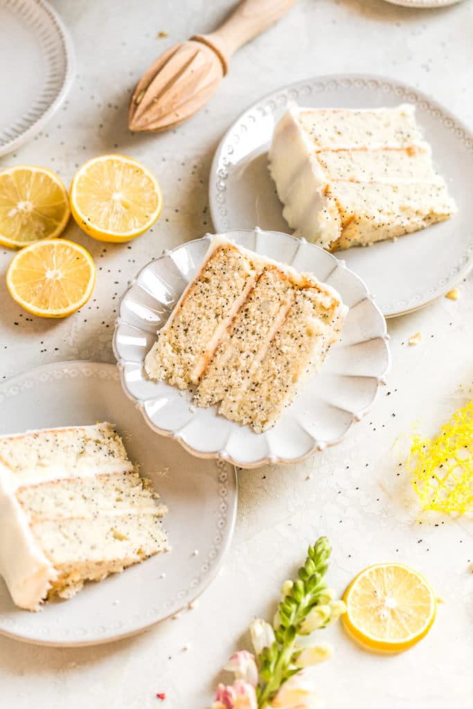 3 slices of lemon poppyseed cake styled on 3 gray plates on a gray background