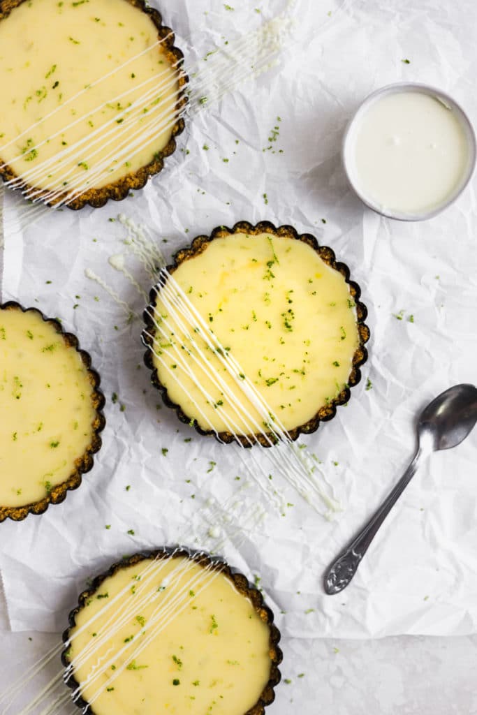 Mini key lime pies drizzled with white chocolate on a white background