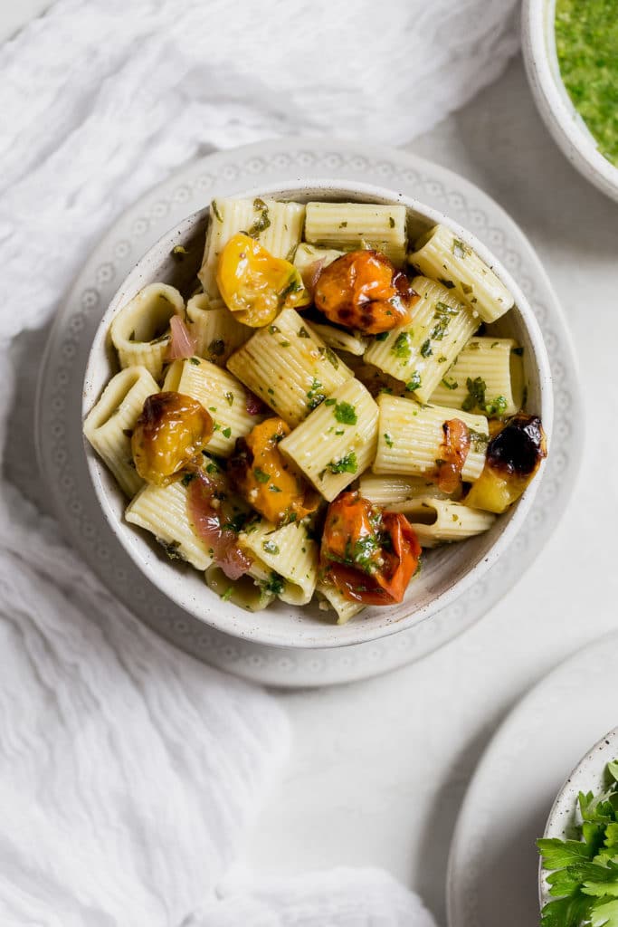 Roasted vegetable pasta salad in a white ceramic bowl on a grey background
