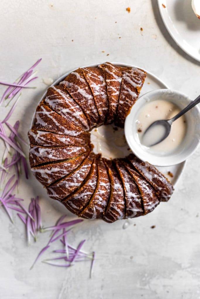 Apple bundt cake with white glaze drizzled next to the bowl of glaze.