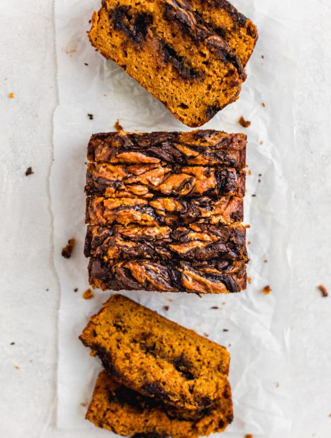 Slices of pumpkin bread with chocolate lined up on a white surface.