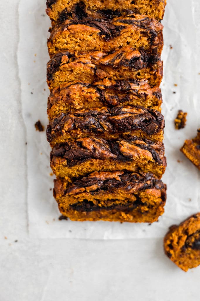 A chocolate pumpkin loaf sliced and put back together on a white surface.