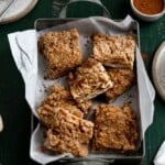 apple pie bars in a tin on a green background