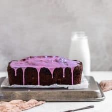 Side view of banana bread with purple glaze dipping down.