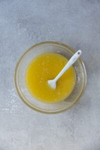 Melted butter, sugar, and eggs mixed in a glass bowl.