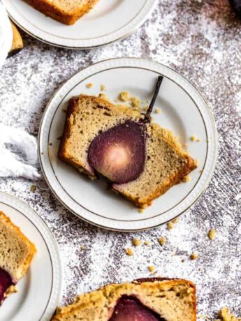 A slice of a cake that has a pear baked inside on a white plate.