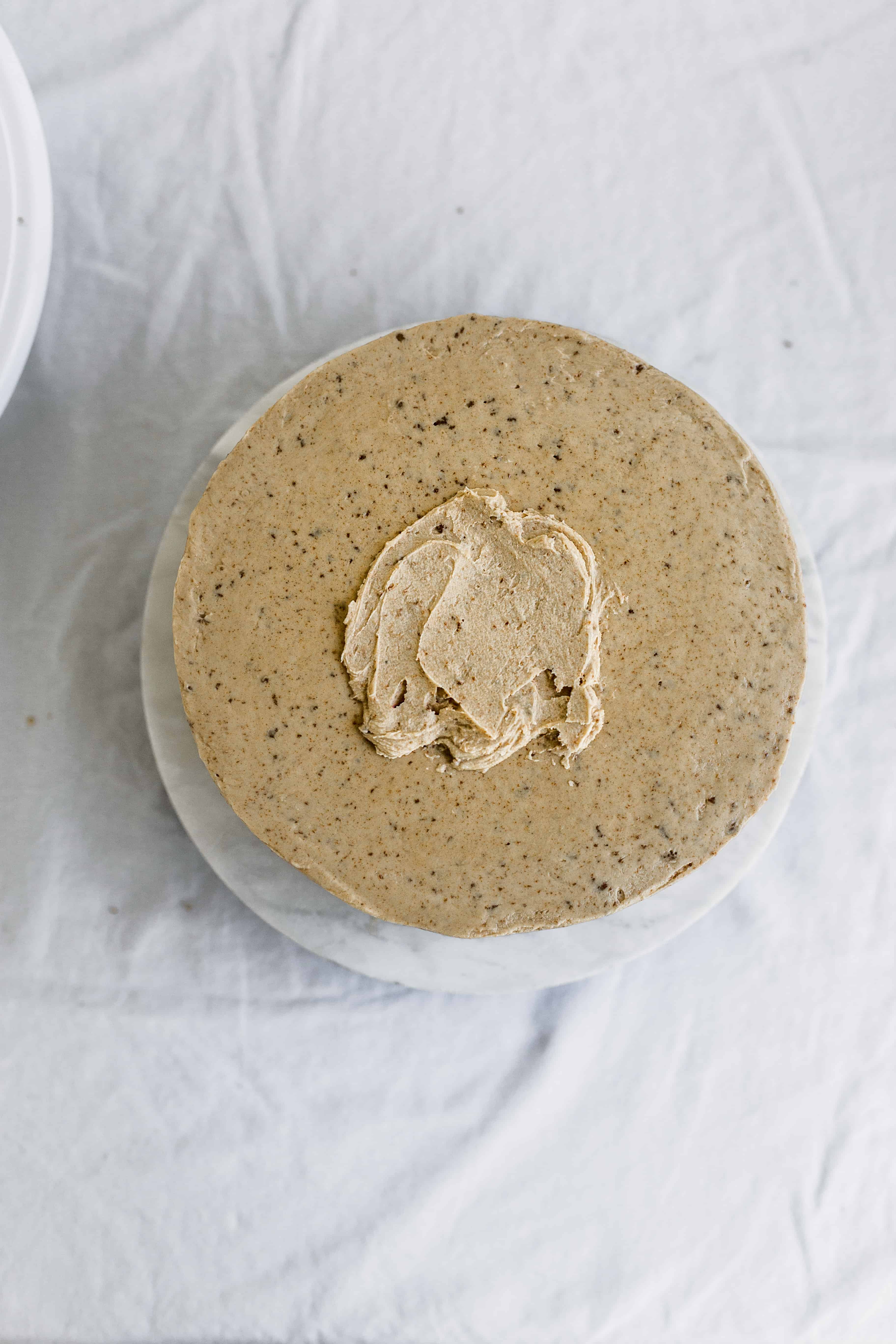 Frosting smoothed onto the top of a beige cake