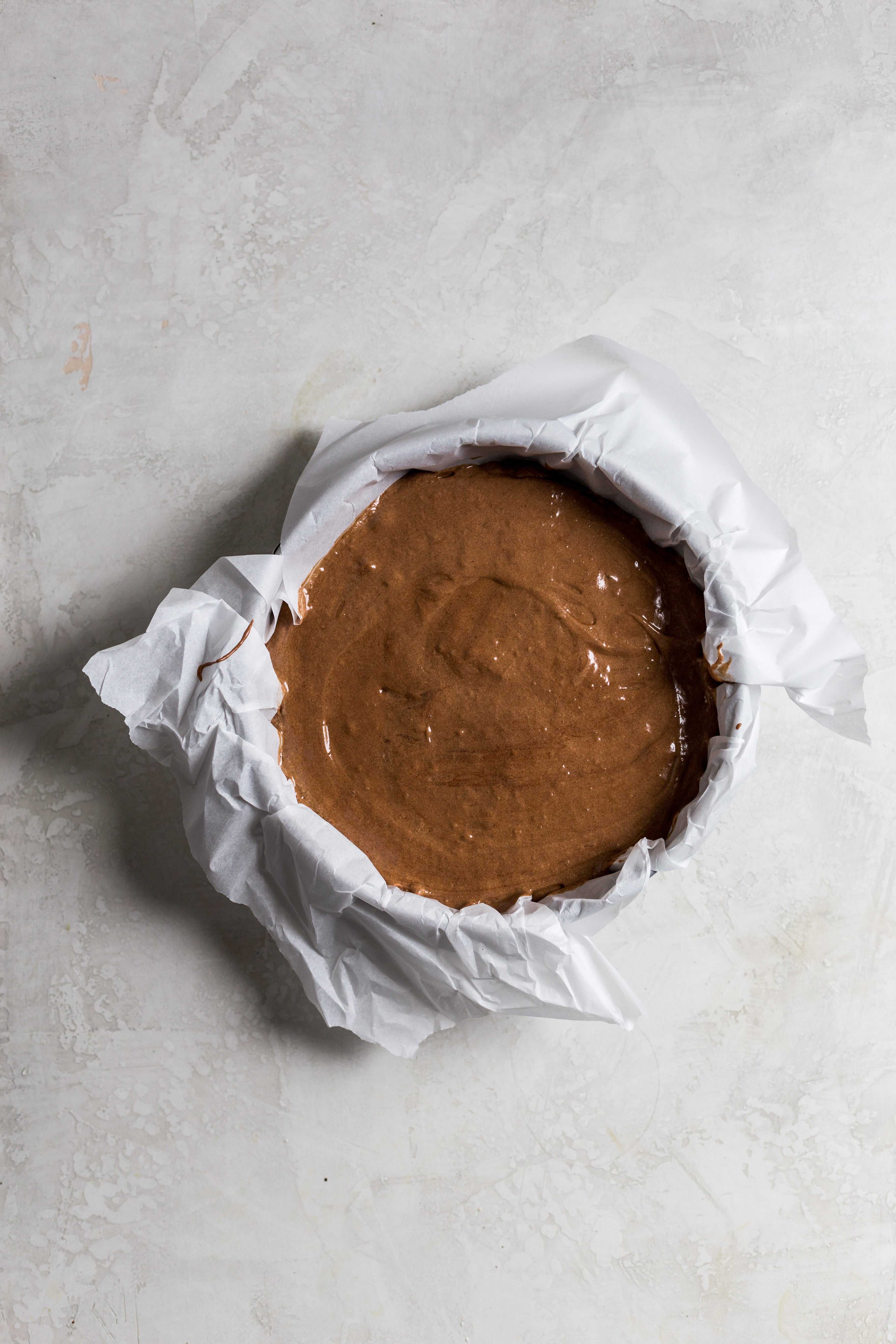Chocolate cake batter in a parchment paper lined spring form pan